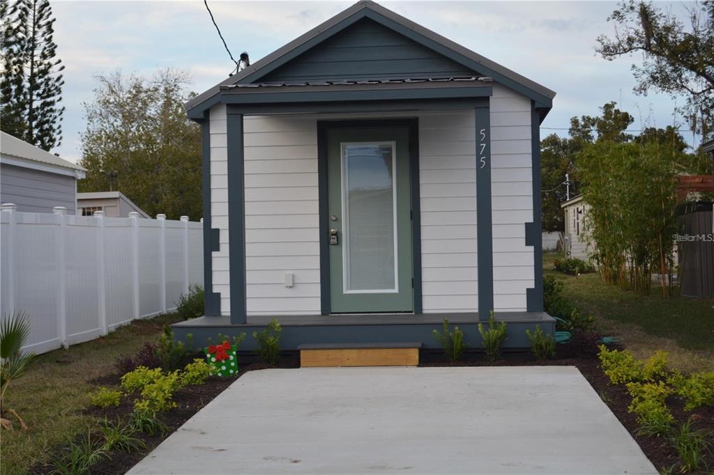 A small, modern house with white horizontal siding, a green door, and a concrete driveway — 575 2ND STREET, OVIEDO, FL