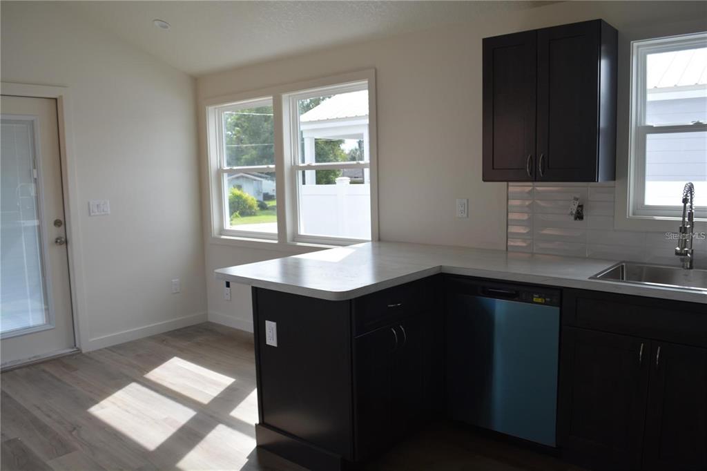 A kitchen with dark cabinets, light countertops, stainless steel appliances, and a view of outdoors — 575 2ND STREET, OVIEDO, FL