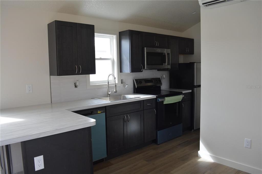 A kitchen features dark wood cabinets, stainless steel appliances, and light-colored countertops — 575 2ND STREET, OVIEDO, FL