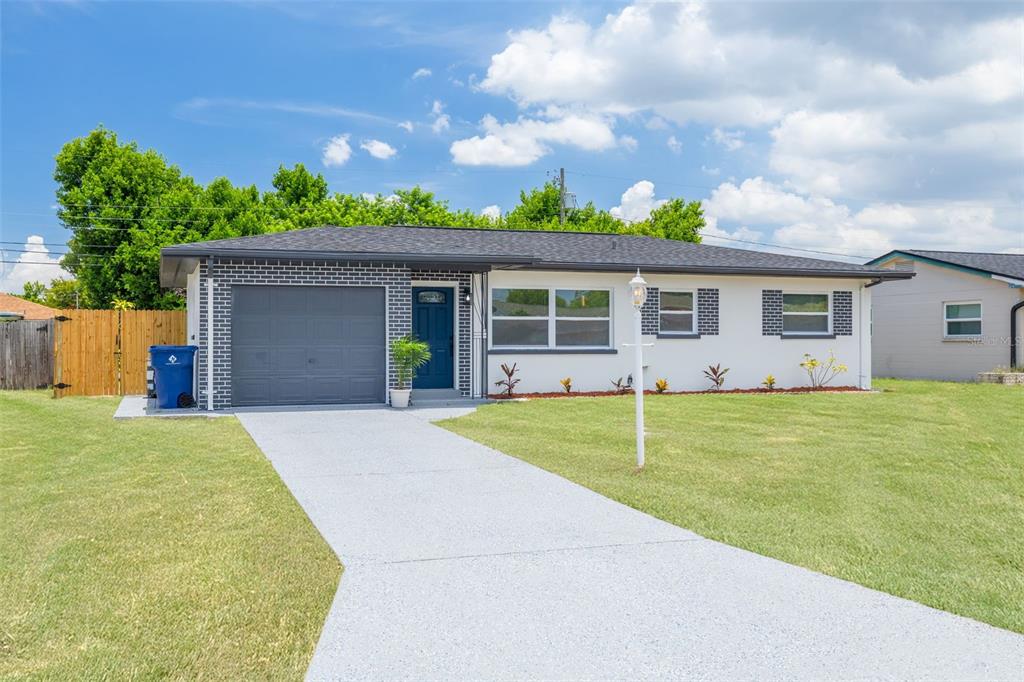 A single-story house with a white stucco facade, gray brick accents, and a concrete driveway — 11189 108TH WAY, LARGO, FL