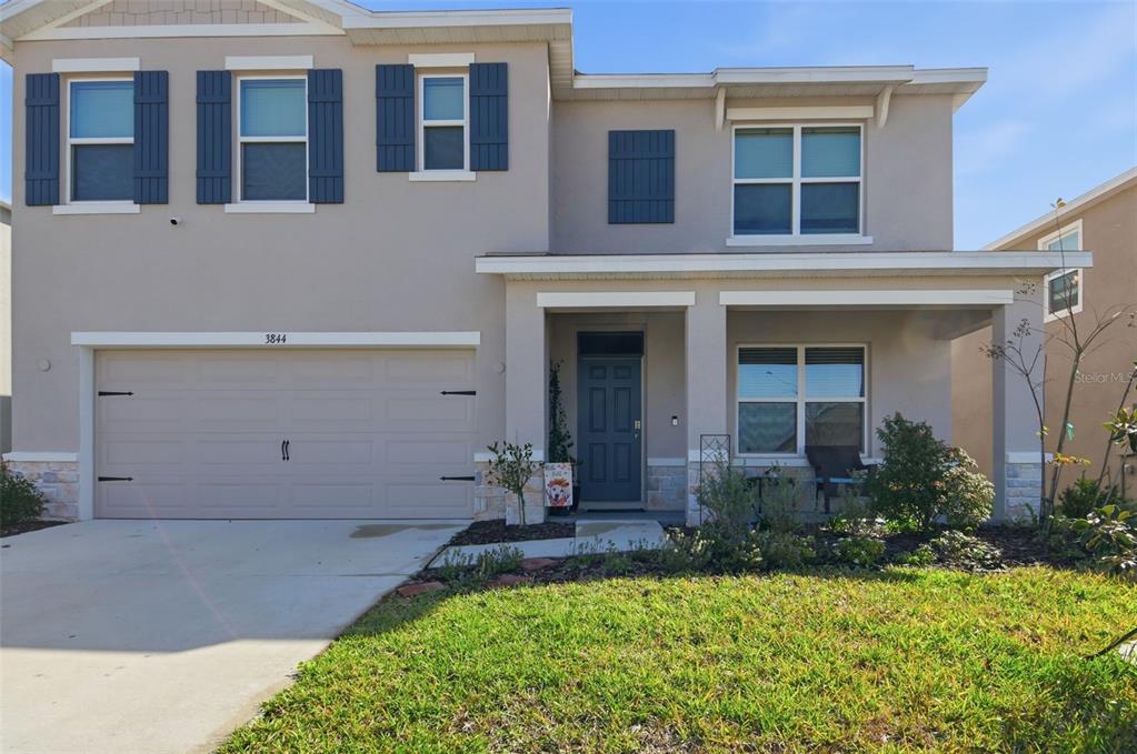 A two-story house with a beige stucco exterior, a two-car garage, and a front porch — 3844 SUNNY SPRING STREET, PLANT CITY, FL