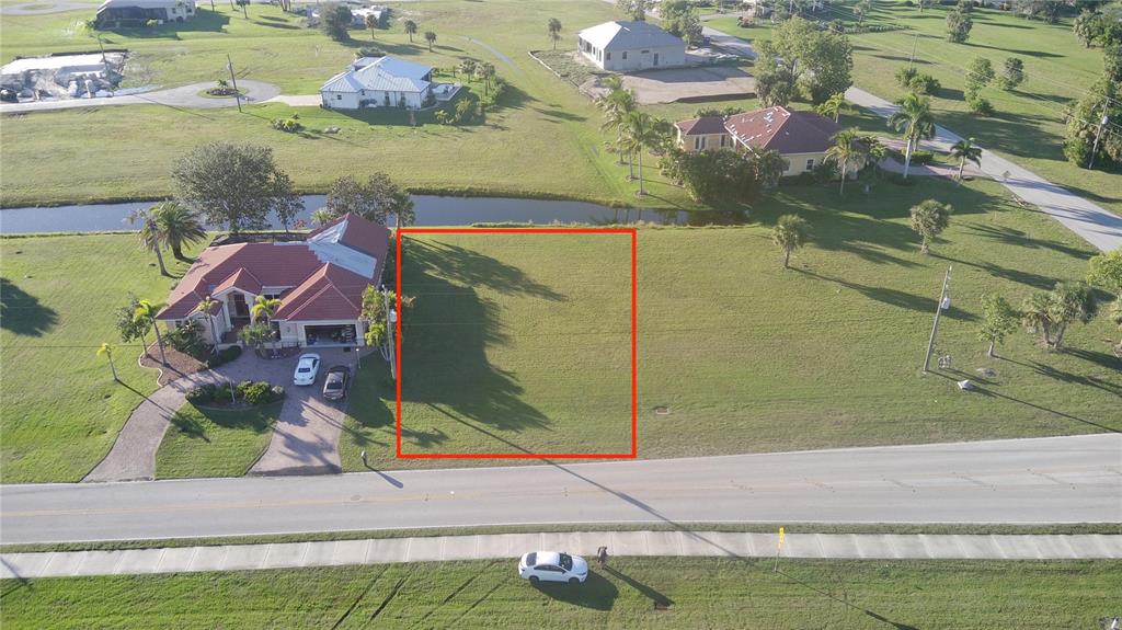 An aerial view shows a vacant rectangular residential lot outlined in red next to a house — 17245 CAPE HORN BOULEVARD, PUNTA GORDA, FL