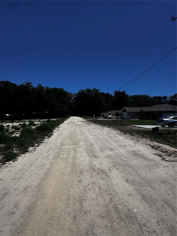 A dirt road leads past a residential house toward a line of trees — 0 SW 104TH LANE, DUNNELLON, FL
