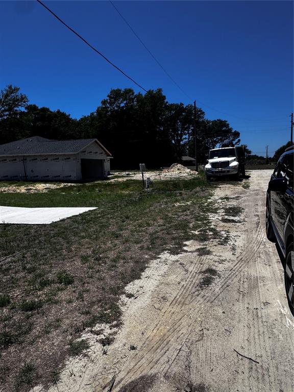 A white truck is parked on a dirt road next to a house under construction — 0 SW 104TH LANE, DUNNELLON, FL