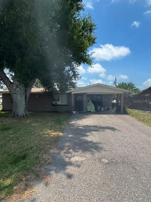 A single-story house with a large tree in the front yard and a covered carport — 8283 PELICAN ROAD, ENGLEWOOD, FL
