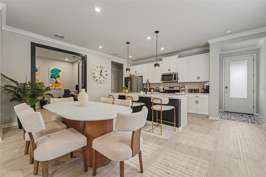A dining area and kitchen feature a white oval table, bar stools, and white cabinetry — 5975 TIMBERDALE AVENUE, WESLEY CHAPEL, FL