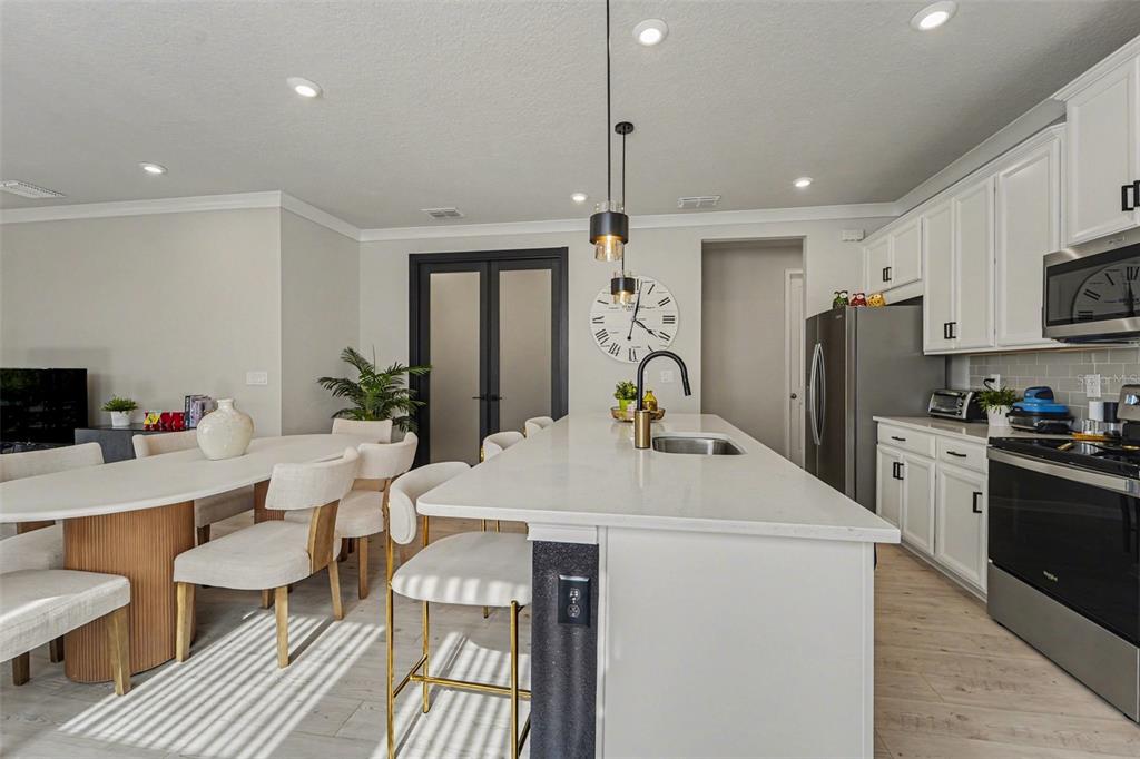 A kitchen and dining area featuring a white island, light wood floors, and white cabinetry — 5975 TIMBERDALE AVENUE, WESLEY CHAPEL, FL
