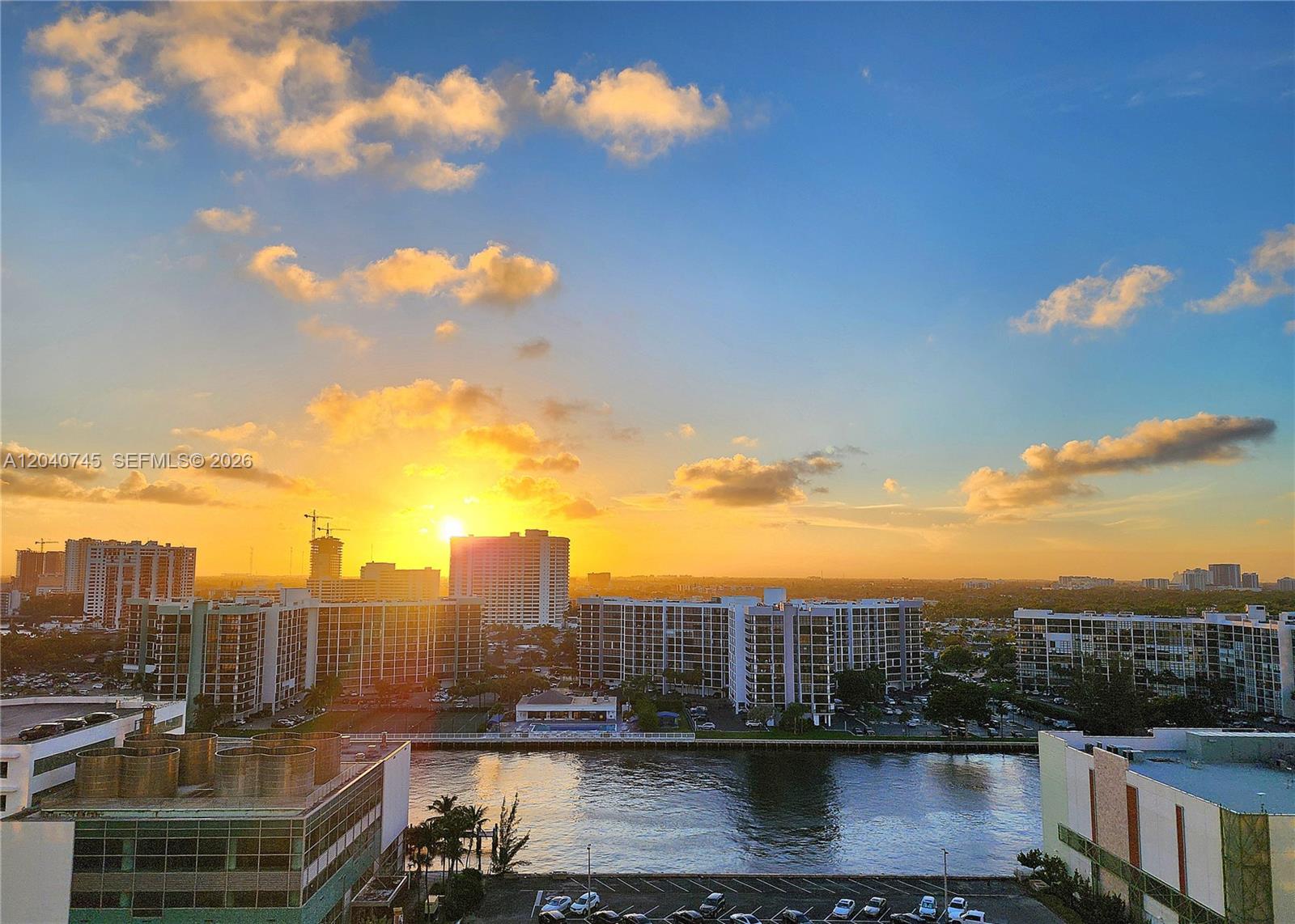 An elevated view shows a sunset over a canal, apartment buildings, and a parking lot — 3505 S Ocean Dr # 1502, Hollywood FL 33019, HOLLYWOOD, FL