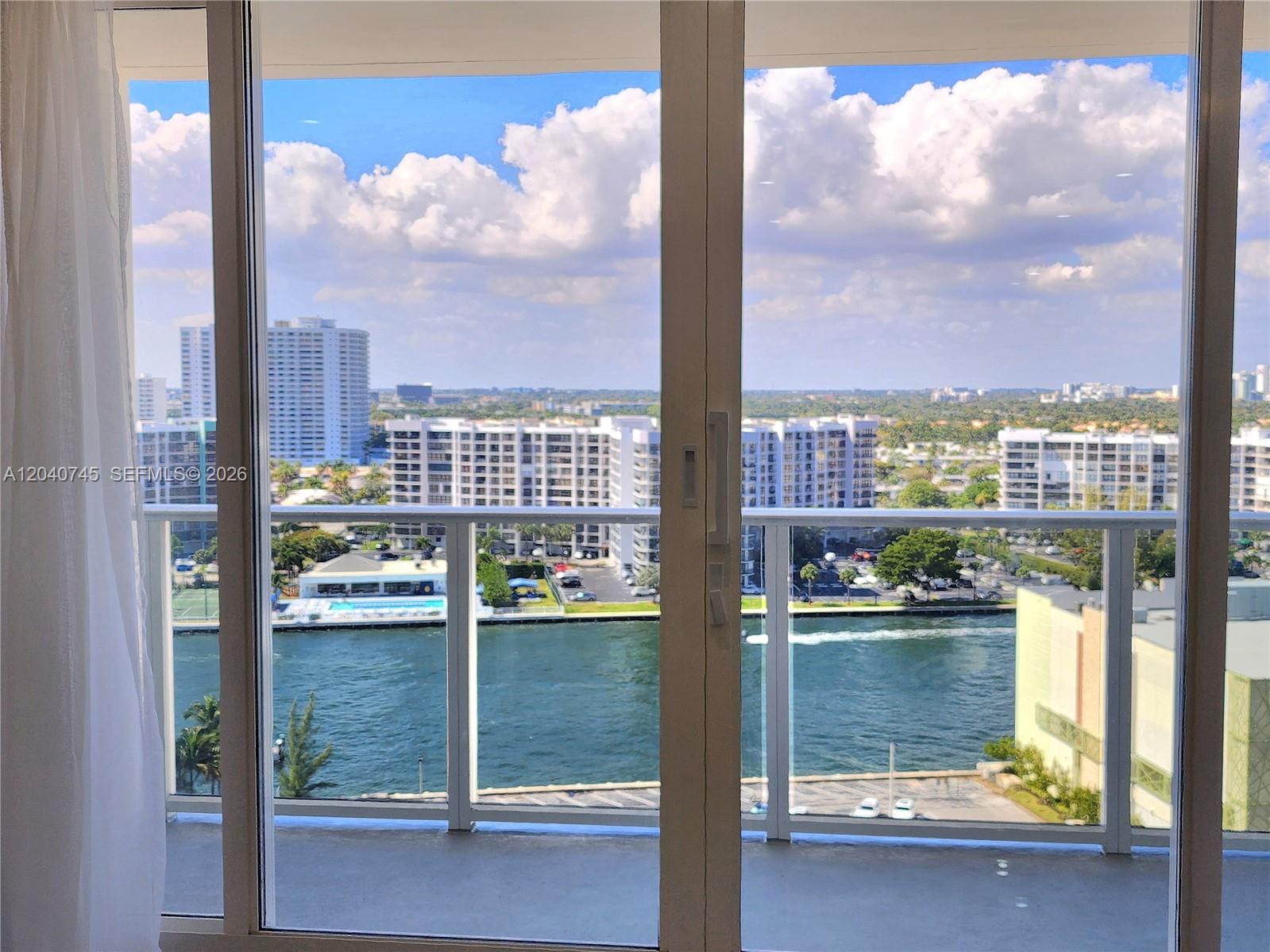 A view of a waterway and city buildings from a balcony through glass doors — 3505 S Ocean Dr # 1502, Hollywood FL 33019, HOLLYWOOD, FL