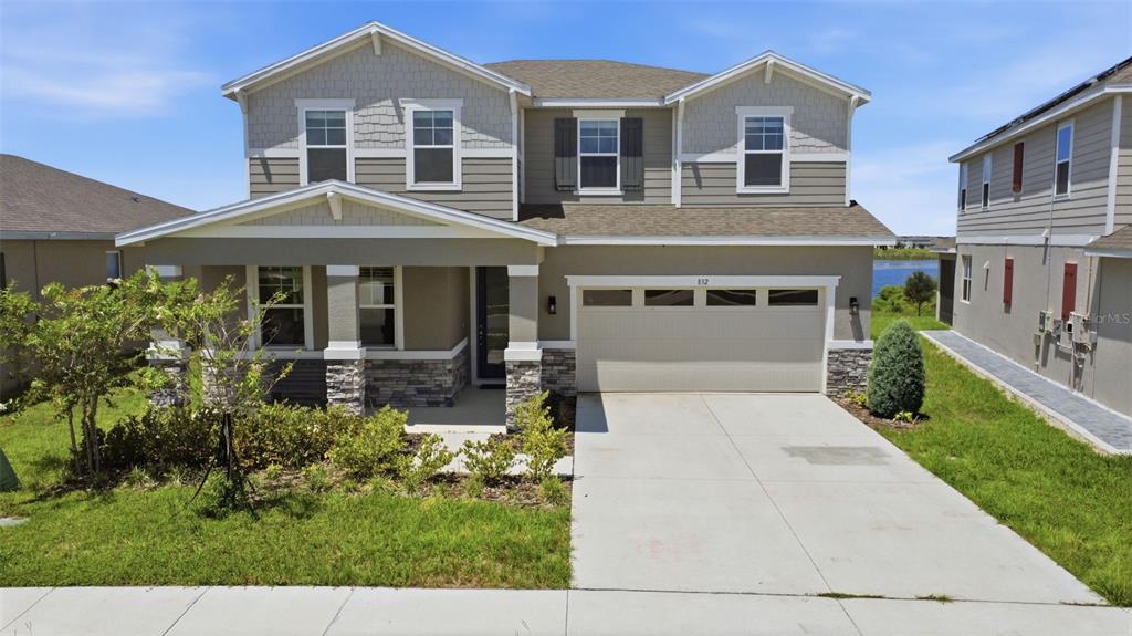 A two-story suburban house with a stone-accented porch, beige siding, and a two-car garage — 832 GRIFFON AVENUE, LAKE ALFRED, FL