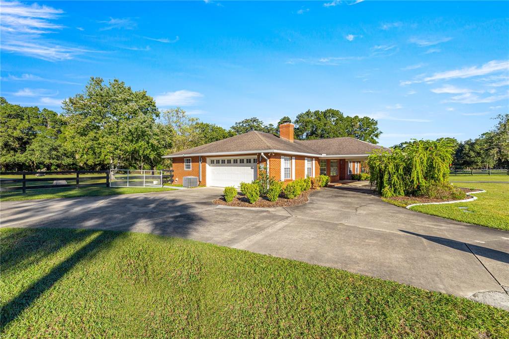 A single-story brick house with a two-car garage and a large concrete driveway — 9812 SW 74TH AVENUE, OCALA, FL
