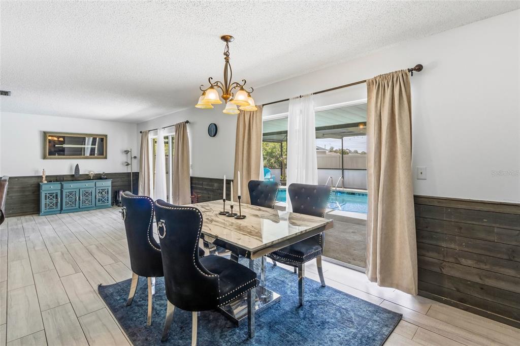 A dining room features a marble-topped table, dark upholstered chairs, and a view of a pool — 5262 WOODRIDGE LANE, SPRING HILL, FL