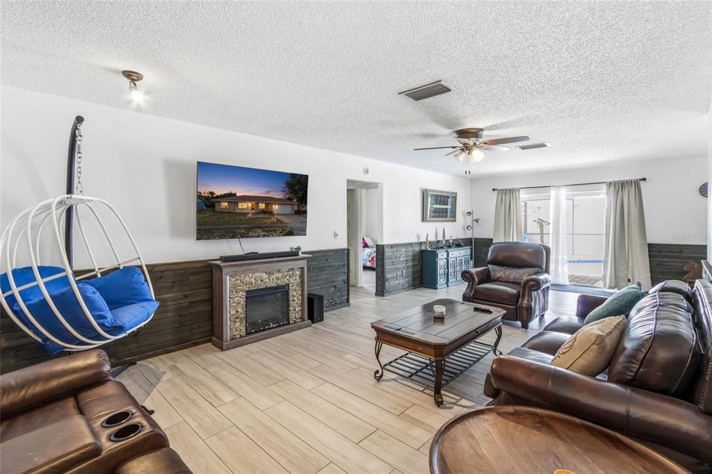 A living room features a stone fireplace, a hanging chair, and dark wood wainscoting — 5262 WOODRIDGE LANE, SPRING HILL, FL