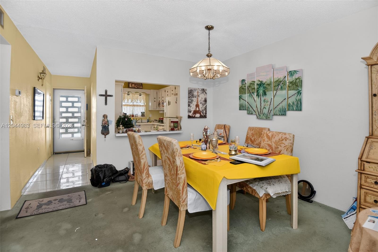 A dining room features a yellow-clothed table, patterned chairs, a chandelier, and a kitchen pass-through — 2711 N HALIFAX AVE # 693, Daytona FL 32118, DAYTONA, FL