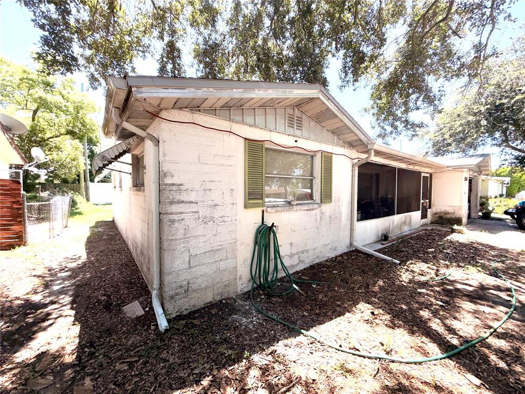 The exterior of a single-story house features white concrete block walls, green shutters, and a screened-in porch — 5136 MECASLIN DRIVE, NEW PORT RICHEY, FL