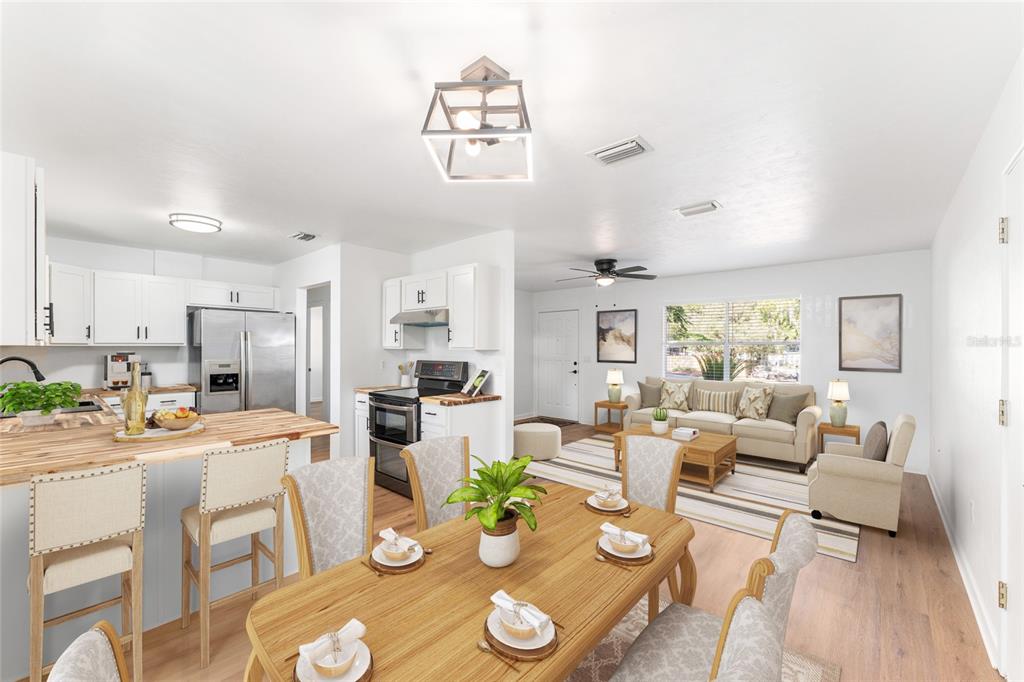 An open-concept kitchen, dining area, and living room featuring white cabinetry and wood-toned furniture — 5701 SW 47TH PLACE, GAINESVILLE, FL