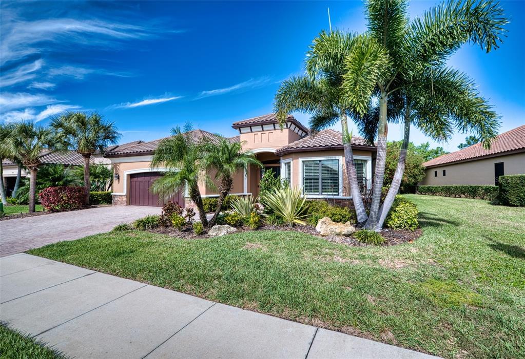 A single-story house with a tile roof, palm trees, and a paved driveway — 10107 WICKER PARK PLACE, PALMETTO, FL