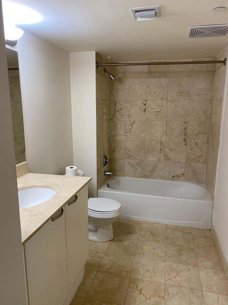 A bathroom featuring a vanity, toilet, and a bathtub with beige marble-style wall tiles — 2101 Brickell Avenue # 504, Miami FL 33129, MIAMI, FL