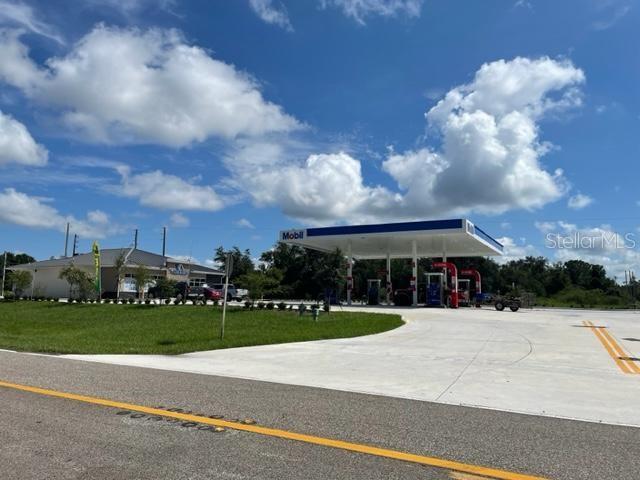 A Mobil gas station with a large canopy stands next to a building under a blue sky — KISSIMMEE WAY, KISSIMMEE, FL