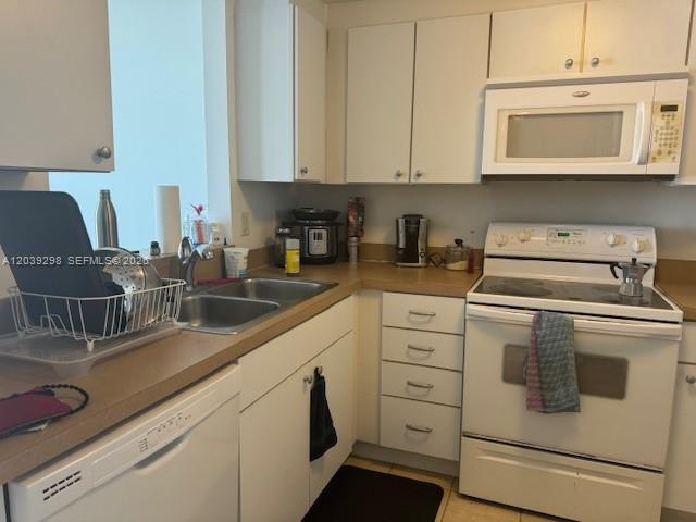 A kitchen features white cabinets, a white stove, a microwave, and a double sink — 1250 S Miami Ave # 1607, Miami FL 33130, MIAMI, FL