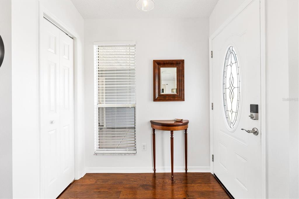 An entryway features a white front door, a window with blinds, and a small wooden table — 406 DEL MAR DRIVE, LADY LAKE, FL