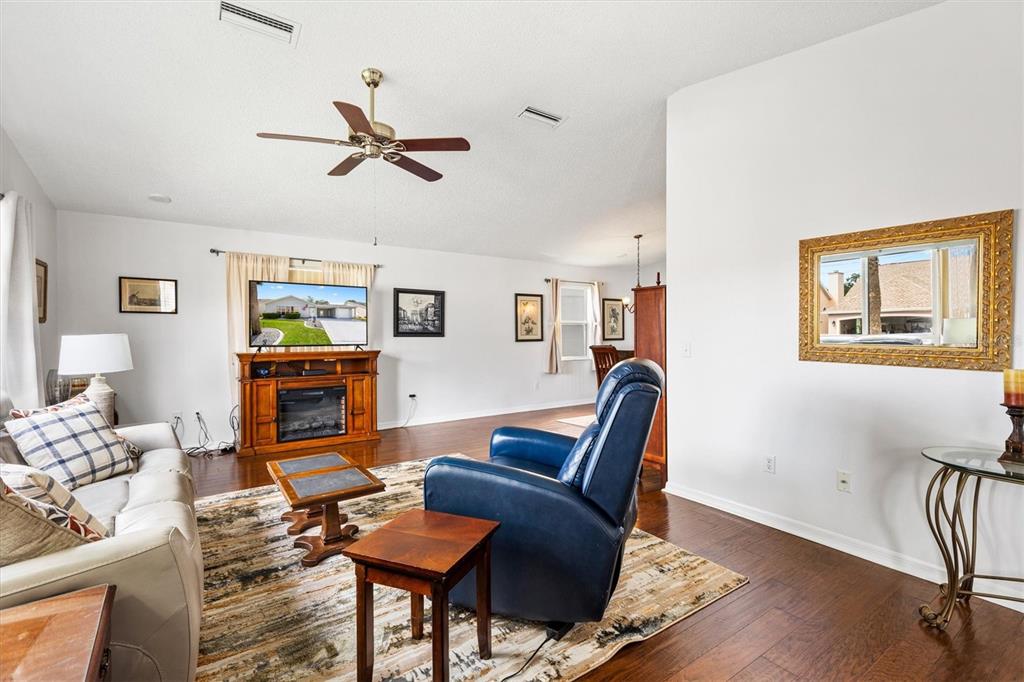A living room features a blue recliner, a light-colored sofa, and a wood media console — 406 DEL MAR DRIVE, LADY LAKE, FL