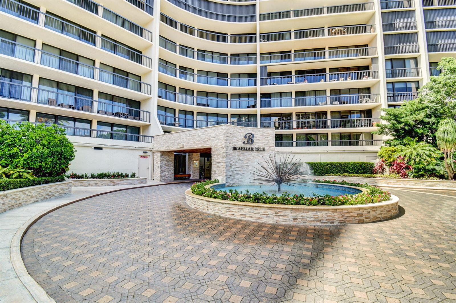 The exterior of a multi-story apartment building features a circular driveway and a central fountain — 4740 S Ocean Boulevard # 702, Highland Beach FL 33487, HIGHLAND BEACH, FL