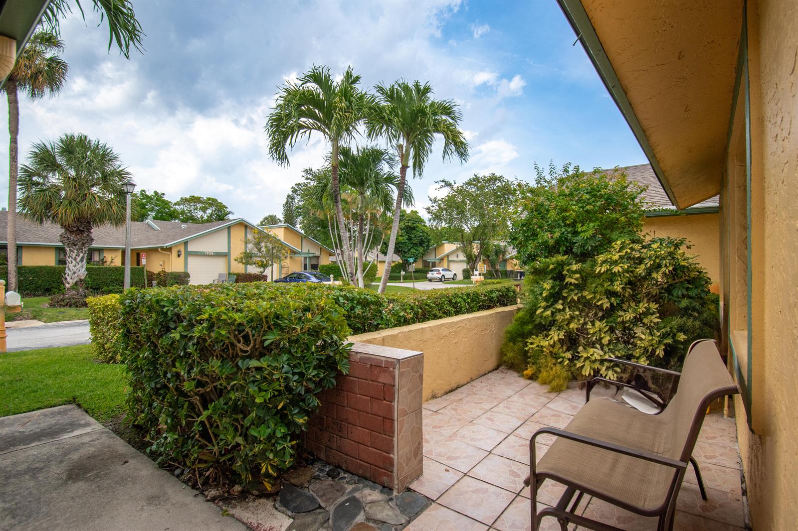 A tiled patio with a metal bench overlooks a landscaped neighborhood with palm trees — 7964 Little Lane, Boca Raton FL 33433, BOCA RATON, FL