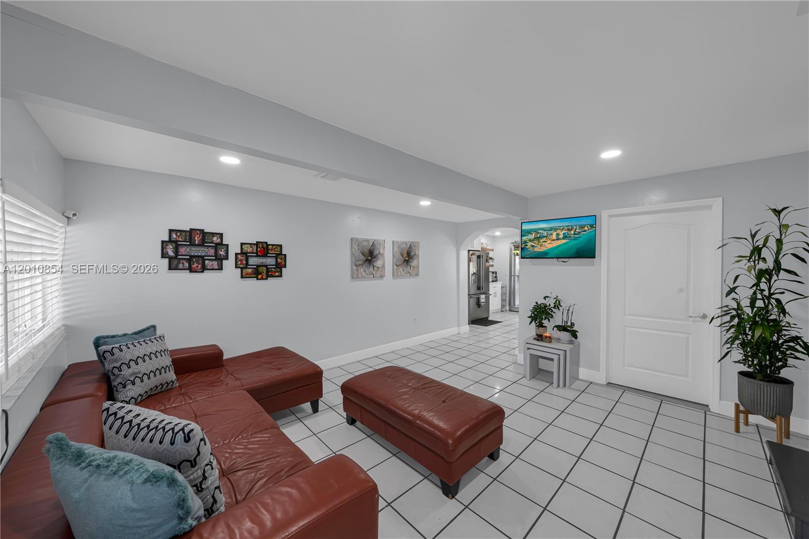 A living room features a red leather sectional, a matching ottoman, and white tile flooring — 11021 SW 4th St, Sweetwater FL 33174, SWEETWATER, FL