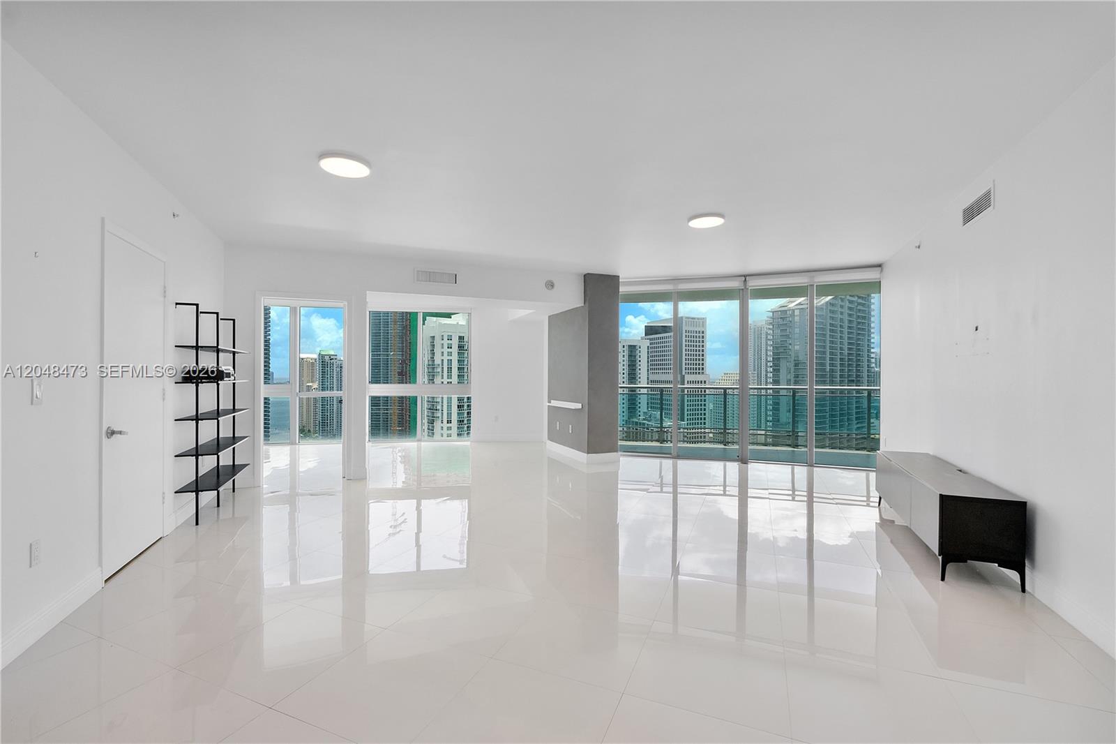 A bright, empty living room features white tile floors, floor-to-ceiling windows, and city views — 350 S Miami Ave # 3702, Miami FL 33130, MIAMI, FL