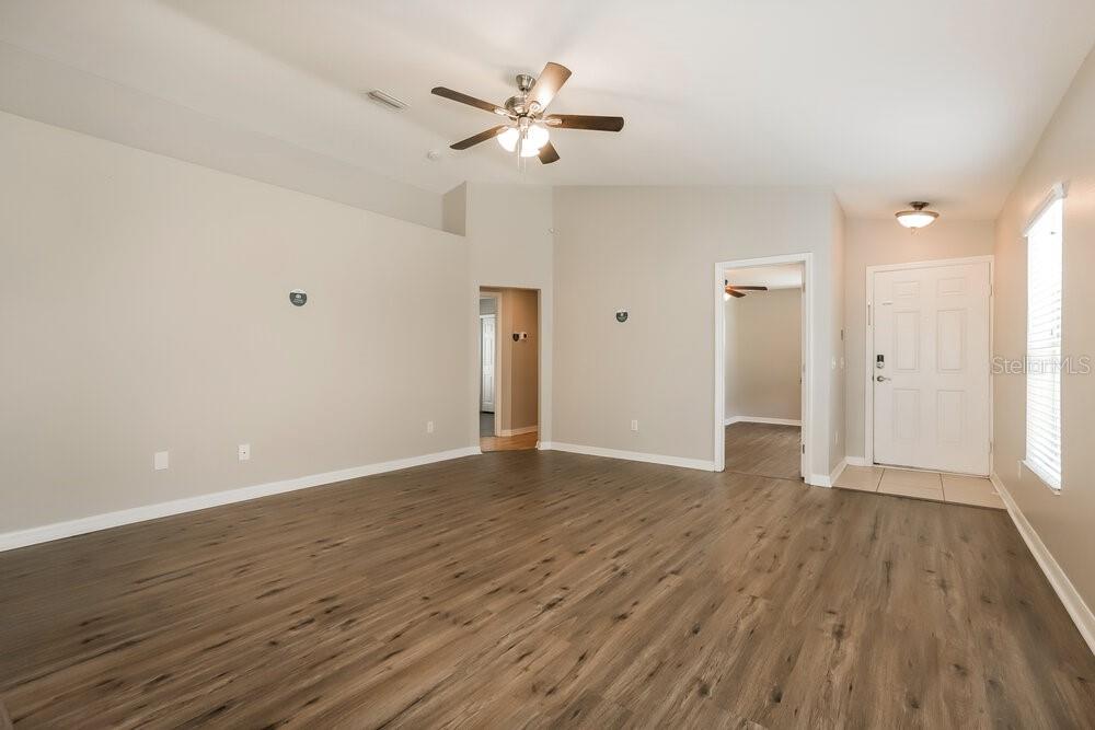 A living room with wood-look flooring, a vaulted ceiling, and a ceiling fan — 906 LARWOOD PINE DRIVE, RUSKIN, FL