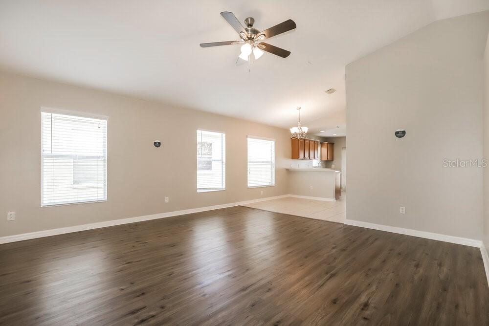 A spacious living room with wood-look flooring, neutral walls, and an open kitchen area — 906 LARWOOD PINE DRIVE, RUSKIN, FL