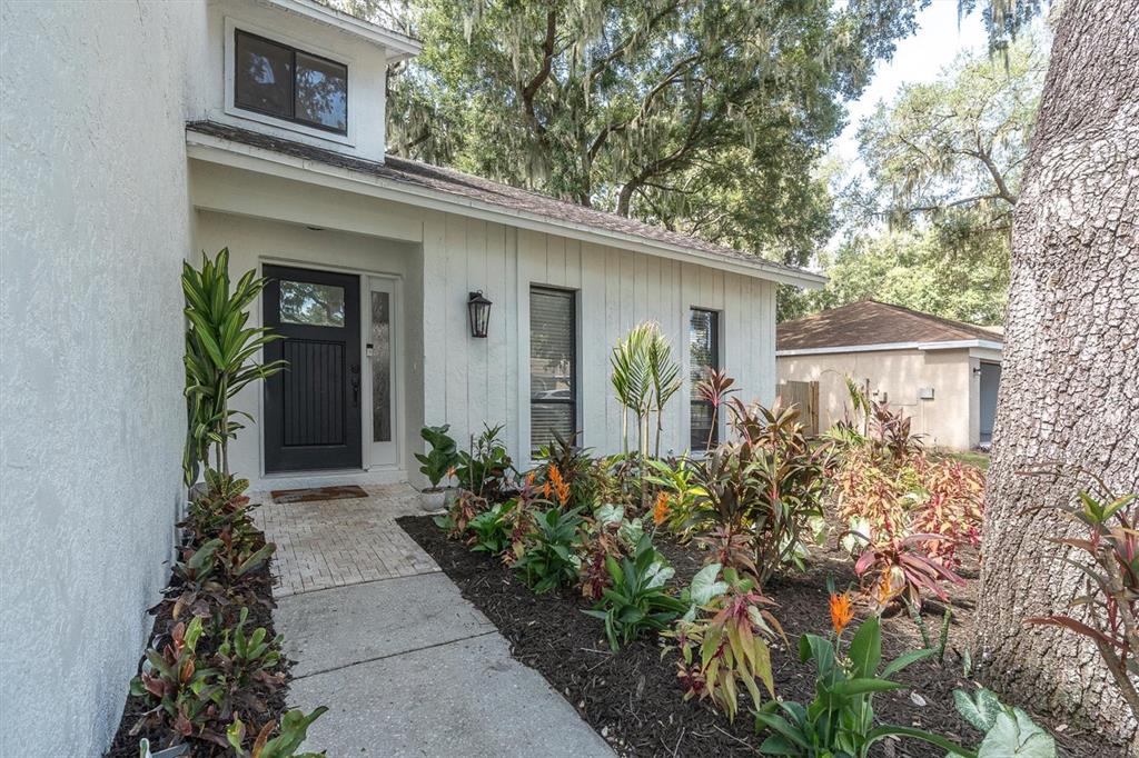 The exterior of a white house features a black front door and landscaped garden beds — 1901 LANDSIDE DRIVE, VALRICO, FL