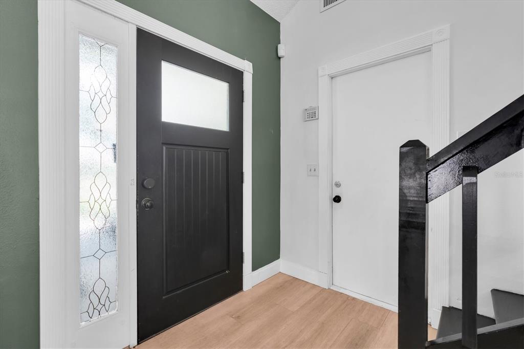 An entryway features a black front door, a white interior door, and light wood flooring — 1901 LANDSIDE DRIVE, VALRICO, FL