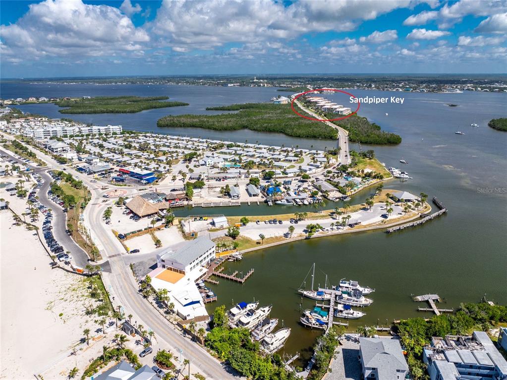 This aerial view shows a coastal community with a marina, bridge, and residential buildings — 1401 BEACH ROAD UNIT 303, ENGLEWOOD, FL