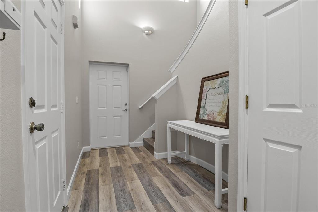 An entryway features wood-look flooring, a white console table, and a staircase leading upward — 5986 TIVOLI GARDENS BOULEVARD, ORLANDO, FL