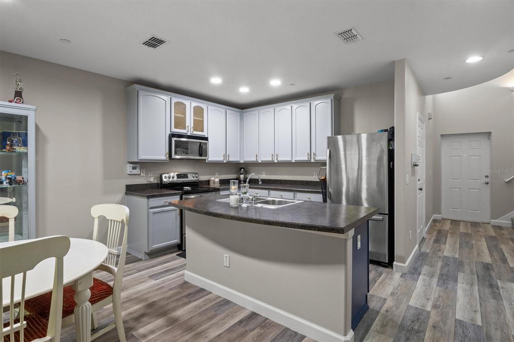 A kitchen features light gray cabinets, a dark countertop island, and wood-look flooring — 5986 TIVOLI GARDENS BOULEVARD, ORLANDO, FL