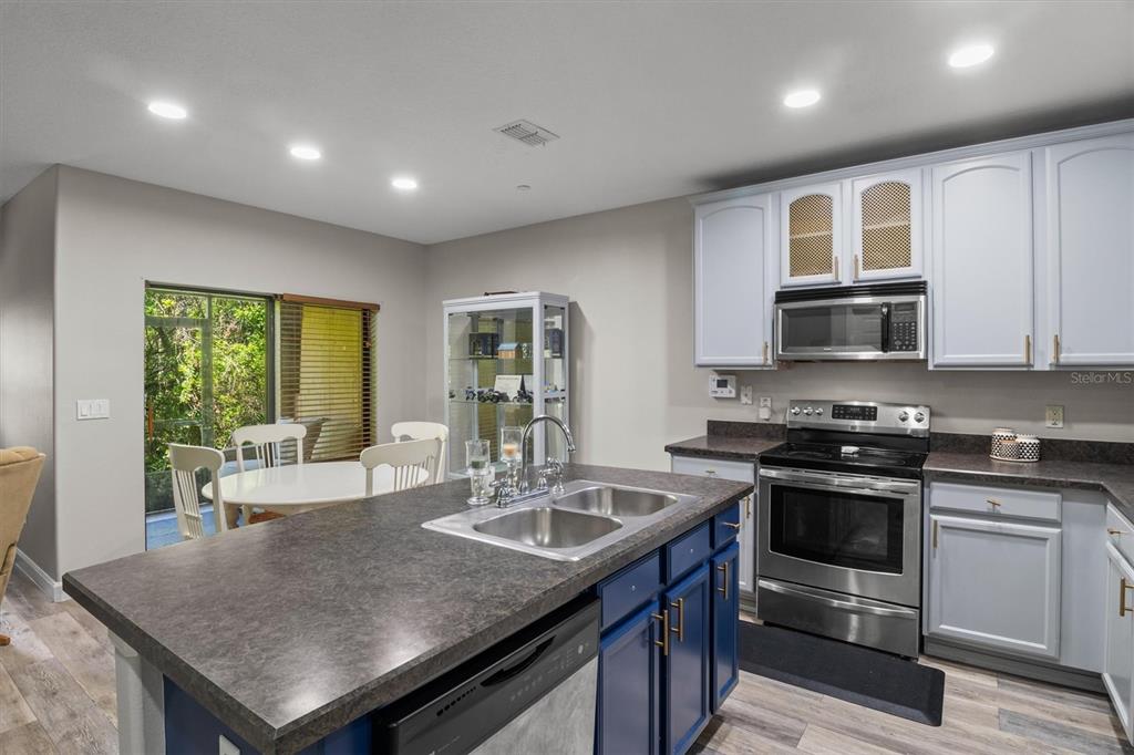 A kitchen features a blue island with a sink, stainless appliances, and light-colored upper cabinets — 5986 TIVOLI GARDENS BOULEVARD, ORLANDO, FL