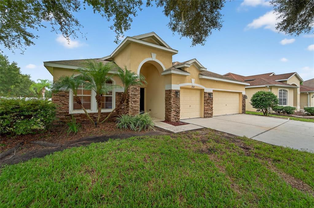 A single-story house with a tan stucco exterior, stone accents, and a two-car garage — 2502 BONTERRA BOULEVARD, VALRICO, FL