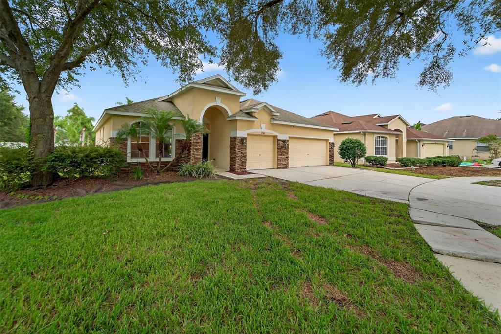 A single-story house with a tan stucco exterior, stone accents, and a two-car garage — 2502 BONTERRA BOULEVARD, VALRICO, FL