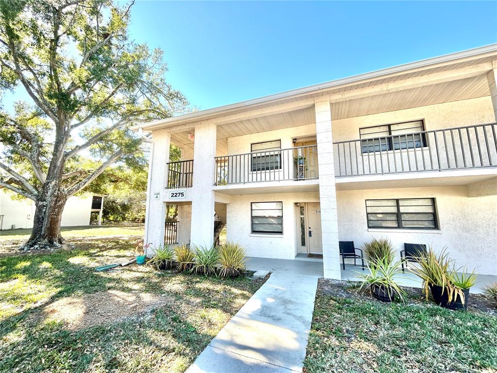 A two-story apartment building exterior features a concrete walkway, balconies, and ground-level patio space — 2275 62ND AVENUE N UNIT 101, ST PETERSBURG, FL