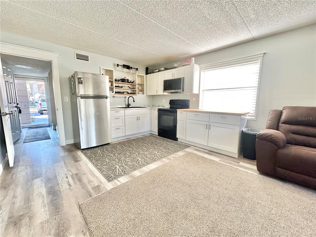 A kitchen features white cabinets, stainless steel appliances, and wood-look flooring in an open space — 2275 62ND AVENUE N UNIT 101, ST PETERSBURG, FL