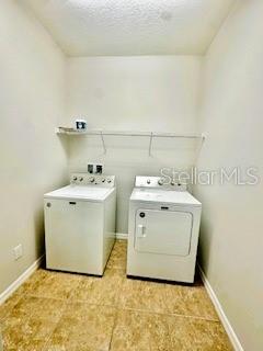 A laundry room features a white washer and dryer beneath a wire shelf — 8107 NORTHLAKE PARKWAY, ORLANDO, FL