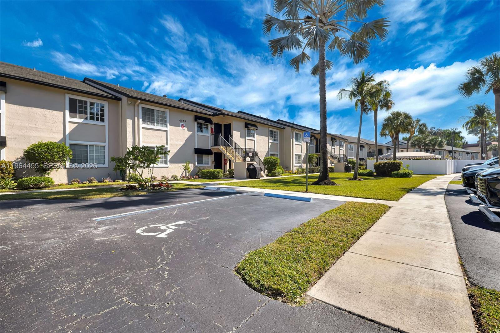 A two-story apartment building features a paved parking lot with a designated handicap space — 4040 Crystal Lake Dr # 105, Deerfield Beach FL 33064, DEERFIELD BEACH, FL
