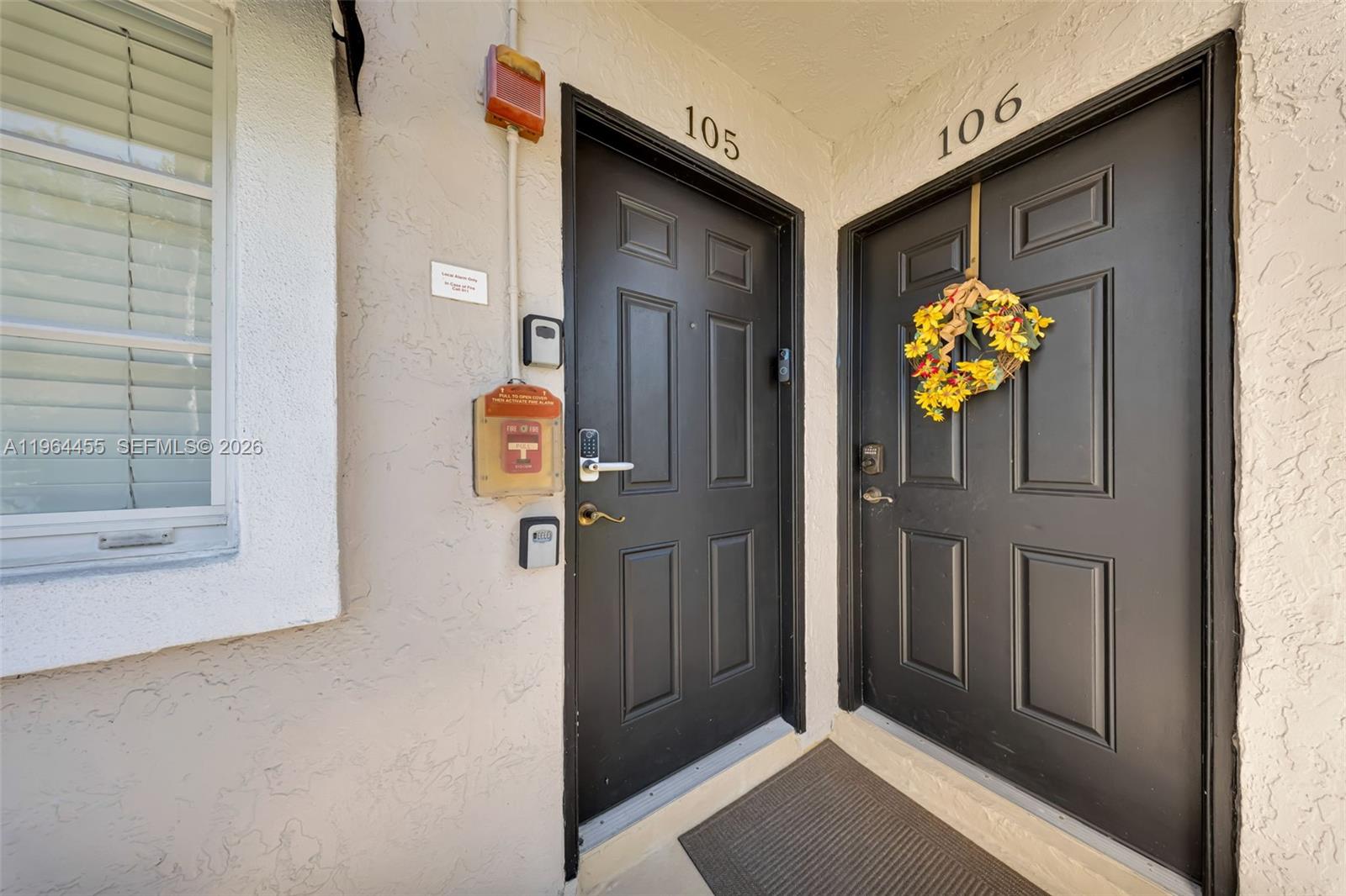 Two black front doors labeled 105 and 106 are set in a stucco exterior wall — 4040 Crystal Lake Dr # 105, Deerfield Beach FL 33064, DEERFIELD BEACH, FL