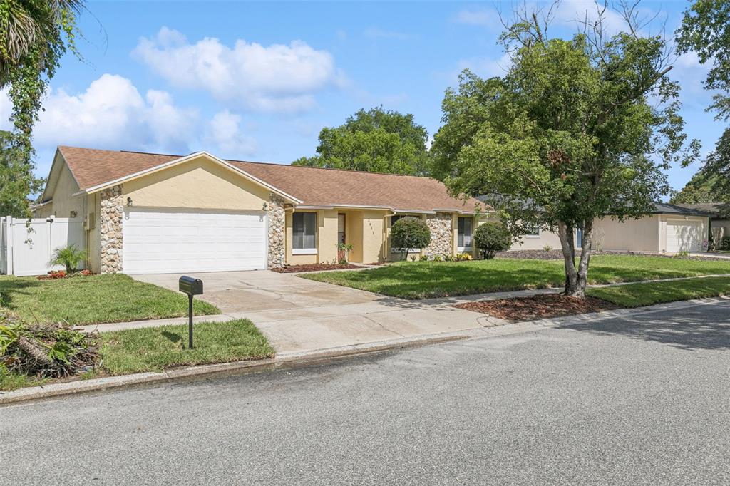 A single-story house with a yellow stucco exterior, stone accents, and a two-car garage — 2911 AUTUMNWOOD TRAIL, APOPKA, FL