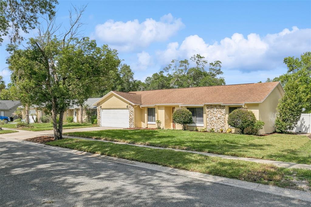 A single-story house with a yellow stucco exterior, stone accents, and a two-car garage — 2911 AUTUMNWOOD TRAIL, APOPKA, FL