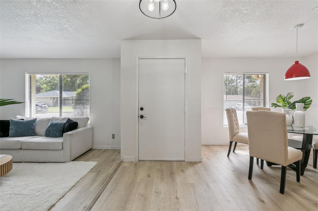 A living and dining area features white walls, light wood flooring, and a central entryway — 2911 AUTUMNWOOD TRAIL, APOPKA, FL