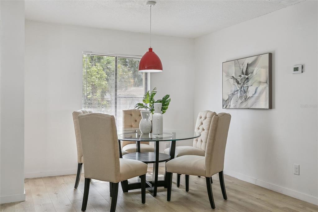 A dining area features a glass table, four tufted chairs, and a red pendant light — 2911 AUTUMNWOOD TRAIL, APOPKA, FL