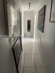 A narrow hallway with white tiled floors leads toward a doorway at the far end — 1489 W 34th St, Riviera Beach FL 33404, RIVIERA BEACH, FL